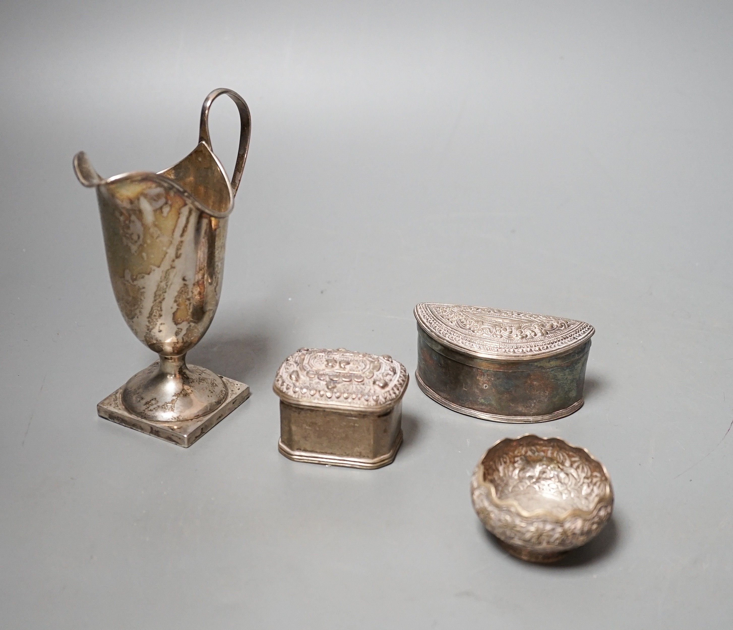 A Edwardian silver helmet shaped cream jug, Mappin & Webb, London, 1905, 13.1cm and three Indian white metal items including two lidded pots.